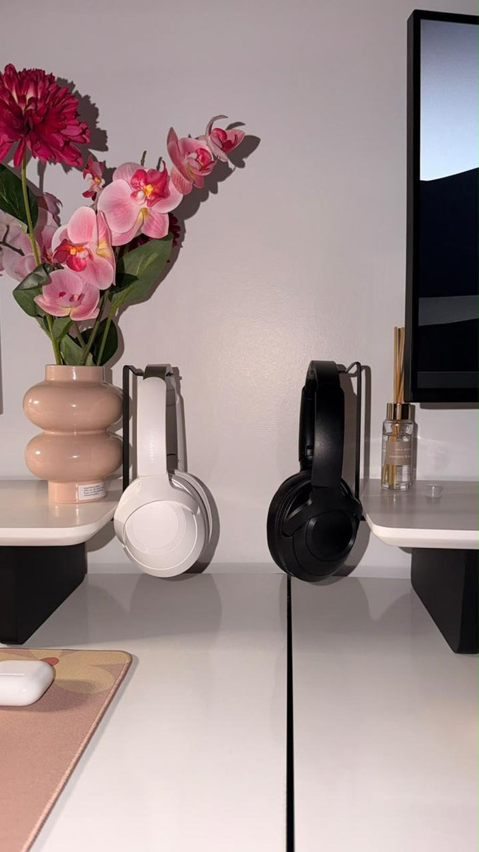 Two headphones hanging from GOMYART headphone stands under a white shelf